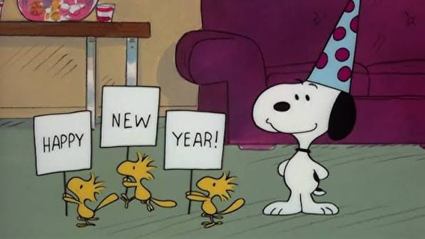 snoopy stands in a living room with a party hat on, while 3 woodstocks stand next to him each holding a “happy new year” sign